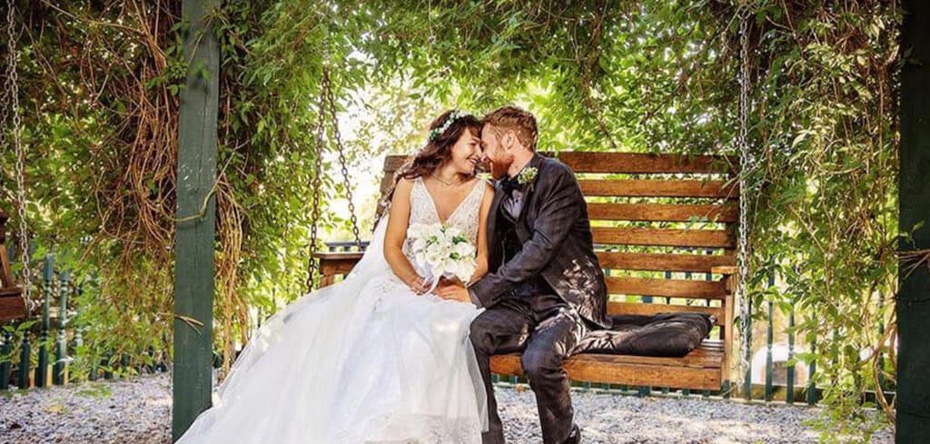 Newlyweds on a garden swing surrounded by greenery at Branxholm Park