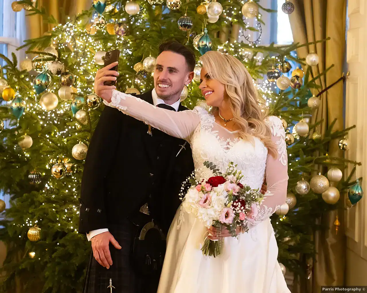 Yvonne and John taking a photograph together beside the Christmas tree