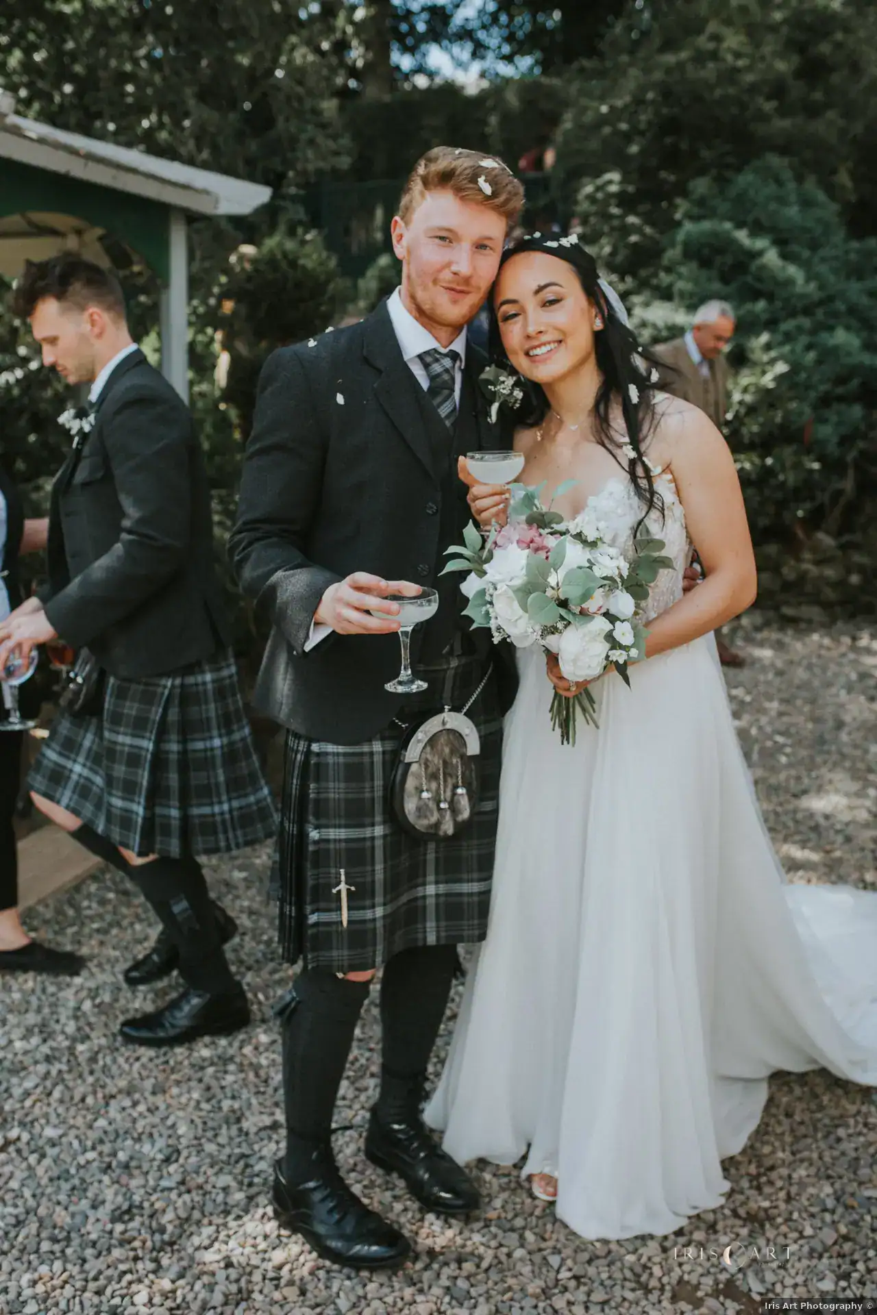 Hannah and Andrew smiling with drinks and confetti in their hair at Branxholm Park