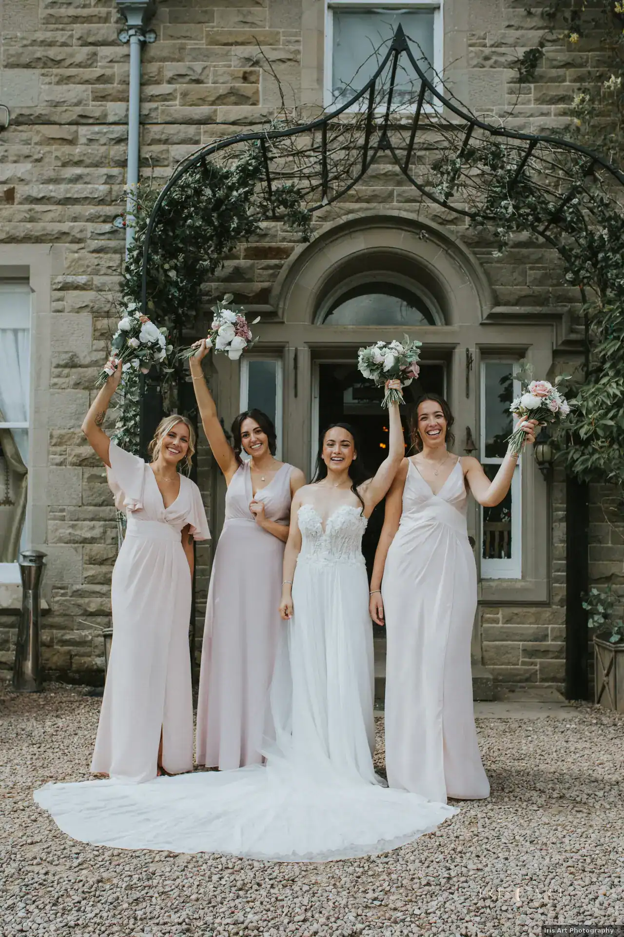 Hannah and her bridal party raising their bouquets outside Branxholm Park