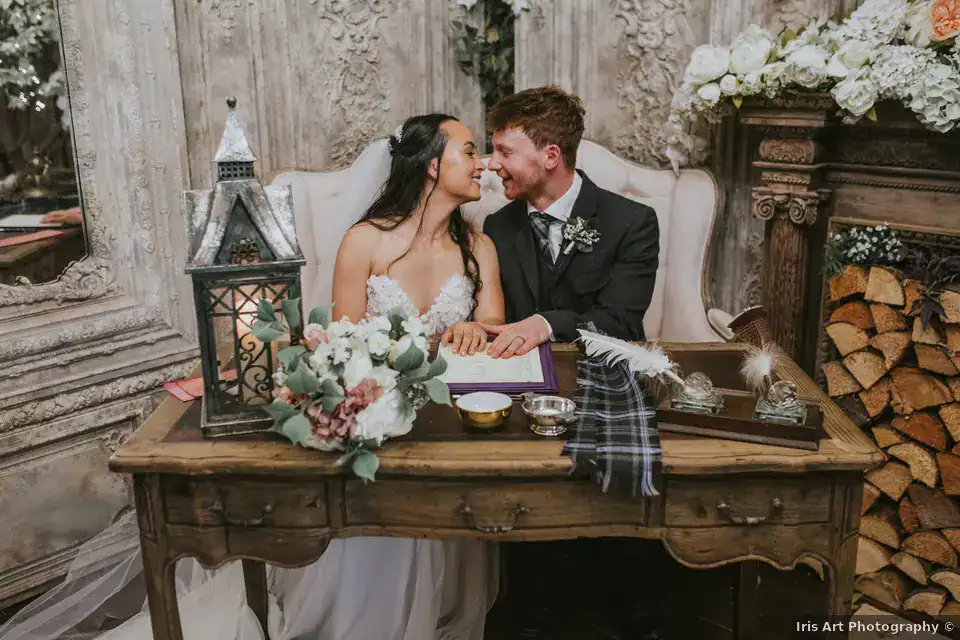 Hannah and Andrew leaning towards each other at their wedding signing table